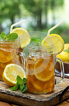 Ice tea in two glass jars with lemon and mint