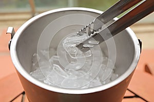 Ice tong used to pick cool ice cubes from steel bucket. concept of healthy and hygiene, summer party full of drinking liqueur