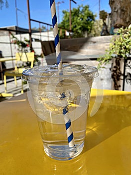Ice water in a plastic to-go cup with a blue and white straw