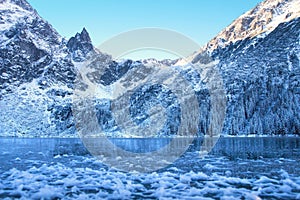 Ice winter mountain lake. Amazing frozen rocky mountains on the lakeshore. Winter background. Winter nature