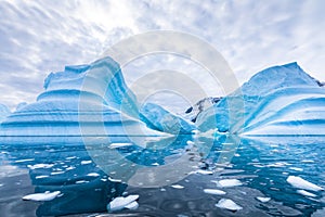 Iceberg in Antarctica floating in the sea, frozen landscape with massive pieces of ice reflecting on water surface, Antarctic