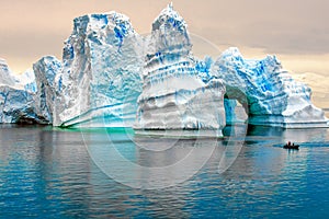 Iceberg in Antarctica, ice castle with Zodiac in front. Huge iceberg sculptured like fairytale castle