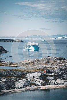 Iceberg with an arch in Antarctic Greenland waters against the backdrop of the mountains of the Arctic Peninsula. Small