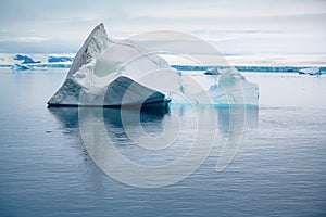 Shiny iceberg floating in calm water on foggy morning in Antarctica. Typical misty day in Antarctica.