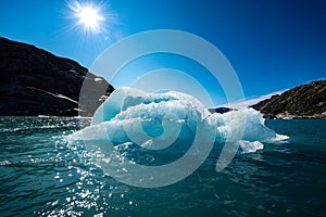 Iceberg floats in crystal clear water of Mosevatnet Lake with Folgefonna Glacier in the background