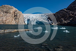 Iceberg floats in crystal clear water of Mosevatnet Lake with Folgefonna Glacier in the background