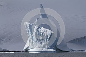 iceberg with a high arrow top near the Antarctic coast on a cloudy day