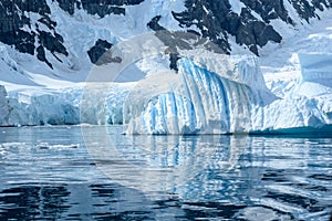 Iceberg with light blue shiny colors and texture reflecting in water of  Southern Ocean, Pradise Bay, Antarctica