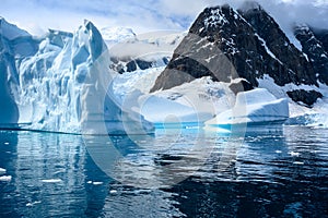 Iceberg with light blue and turquoise shiny colors and texture reflecting in dark water of Southern Ocean, Pradise Bay, Antarctica