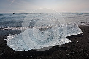 Iceberg pieces from a glacier calving on a black sand beach