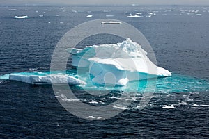 Iceberg in sunlight shining in white and turquoise in dark blue Arctic Ocean, Greenland