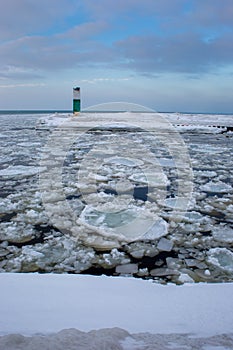 Icebergs drifting in icy water with lighthouse in background