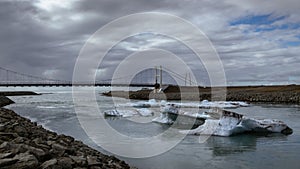 Icebergs floating on the river from the Jokulsarlon Glacier Lagoon to the ocean, bridge. Iceland