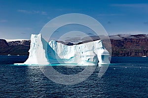 Icebergs in front of Seashore with snow covered Mountains and Fog, Greenland. Huge Iceberg building with tower.