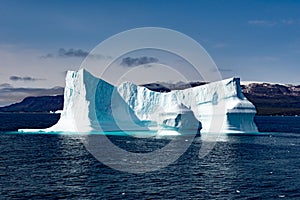 Icebergs in front of Seashore with snow covered Mountains, Greenland. Huge Iceberg building with tower.