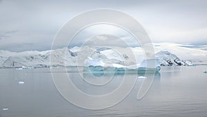 Icebergs and glaciers in Antarctica. Beautiful blue iceberg with mirror reflection floats in open ocean. Global Climate