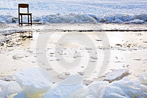 Icebound chair near ice hole in frozen lake