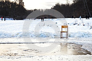 Icebound chair near opening water in frozen lake photo