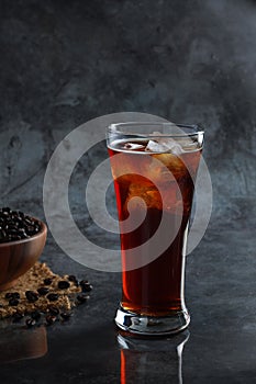 Iced Americano coffee in the glass with coffee beans in background. Diet drink or no sugar concept