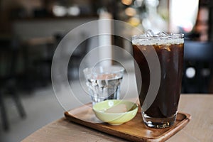 Iced black coffee on wooden tray in coffee shop