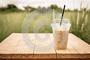 Iced blended frappucino in plastic cup on wood table. Iced coffee