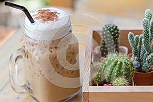 Iced cappuccino with cactus in coffee shop vintage color tone. Coffee and hobby concept. Close up and soft focus.