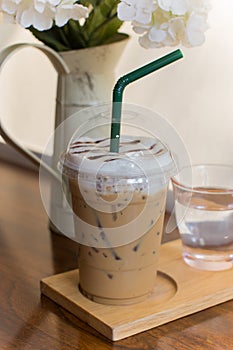 Iced Capuccino coffee on the wood table with flowers.