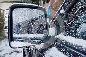 An iced car side mirror with snow. Winter has come