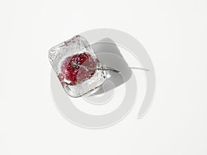 Iced cherry inside an ice cube, isolated on white background