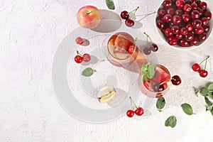 Iced cherry tea or cocktail with mint and lbd,recipe for refreshing summer drink.Glass with apple fruit lemonade on light concrete