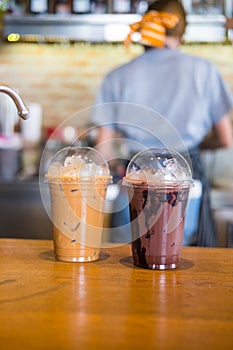 Iced chocolate and iced mocha on table with blurred back view of baretta