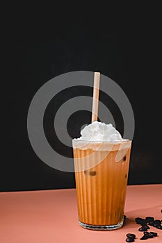 iced coffee or cold caffeine drink with whipping cream and straw on color background