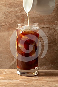 Iced coffee with cream on a beige ceramic table