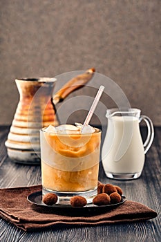 Iced coffee with cream on dark wooden background