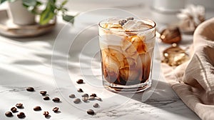 Iced coffee with cream in a glass on marble table. Coffee beans scattered on the table