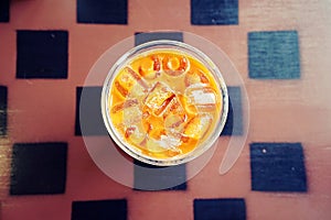 Iced coffee with ice cubes in a cup on wooden background, Top view with copy space.