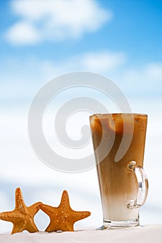 Iced coffee latte with starfish on a beach ocean and seascape