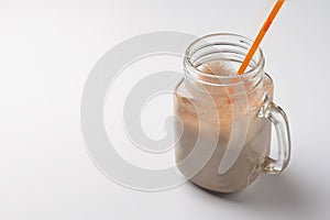 Iced coffee with milk in vintage jar mug with a plastic straw. Isolated over white background