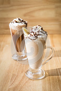 Iced coffee milkshakes on a wood table with a wood background