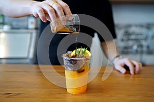 Iced coffee with orange - A plastic glass of espresso shot mixed with orange juice and craft soda on blurred background.