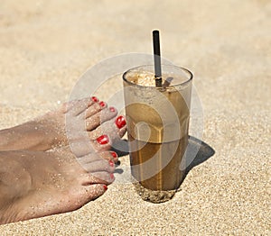 Iced coffee on a sandy beach background