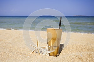 Iced coffee on a sandy beach background