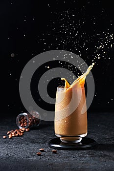 Iced Coffee with Splash in Tall Glass on Dark Background. Concept Refreshing Summer Drink