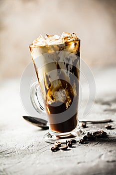 Iced coffee in a tall glass with cream poured over