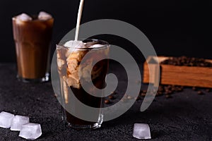 Iced coffee in a tall glass with cream poured over