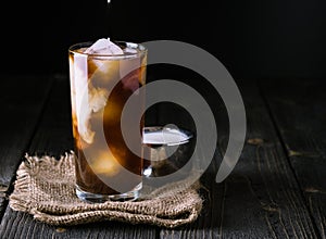 Iced coffee in a tall glass on jute background.