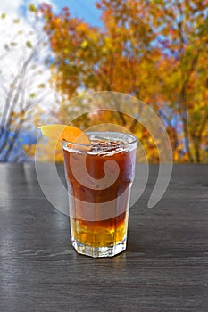 Iced coffee in a tall glass with peach on a wooden table