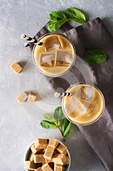 Iced coffee in tall glasses with cream and pieces of sugar, mint