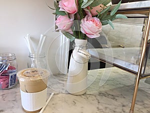 Iced coffee and vase of pink roses