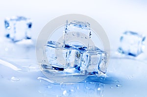 Iced cubes melting on a blue table with reflection. Water. Melting of ice.